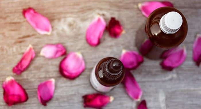 rose petals next to essential oil bottles