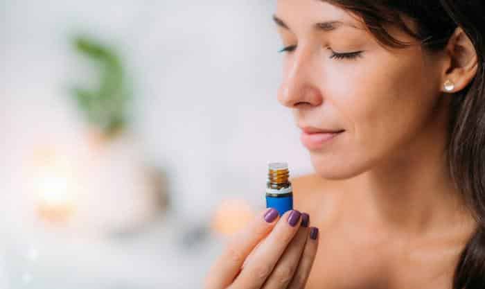 young woman inhaling essential oil from bottle