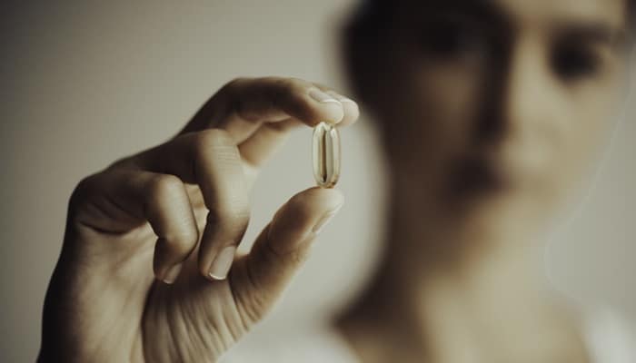woman showing vitamin e pill