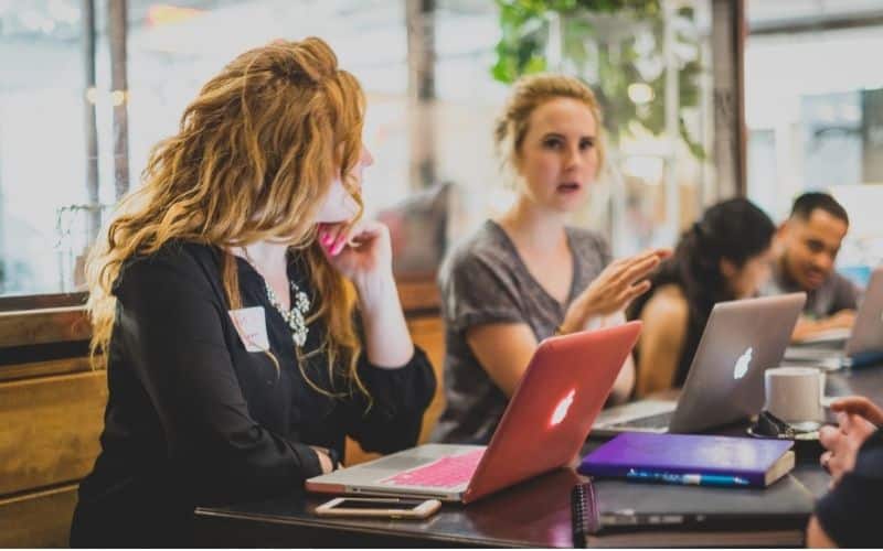women with laptops talking to each other in coffee shop