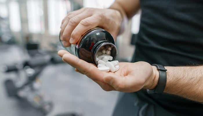 man at gym pouring supplements into hand