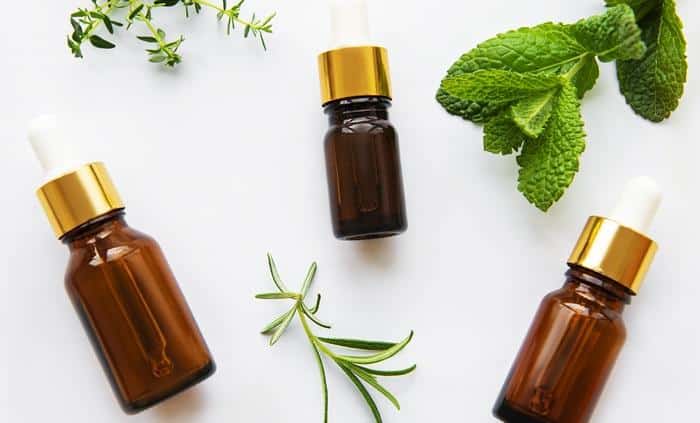 mint and thyme leaves next to essential oil bottles