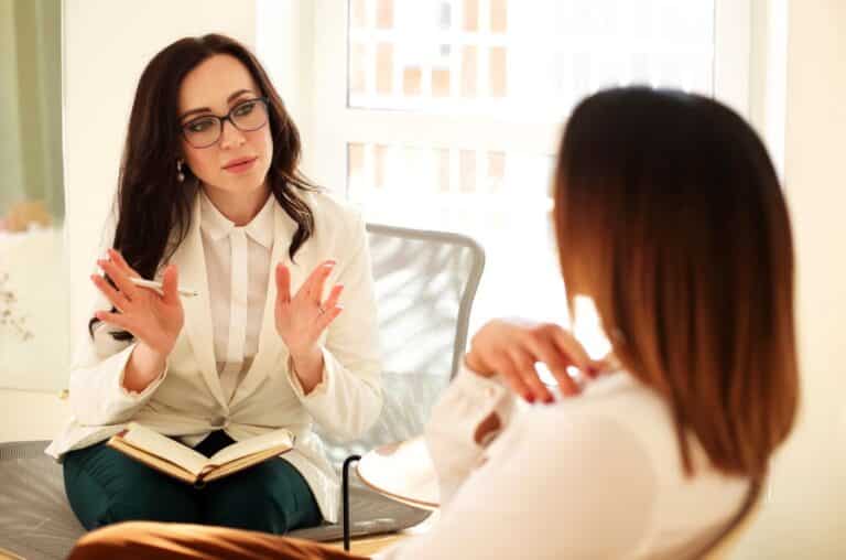 female therapist with pen and notebook conversing with female client