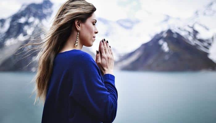 woman praying with snow-covered mountains in background