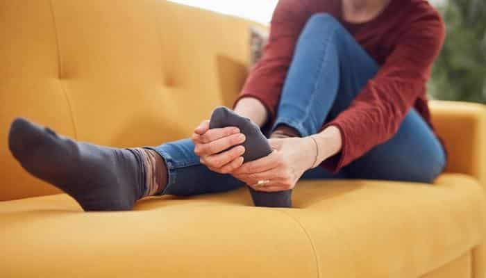 woman with neuropathy holding foot in pain