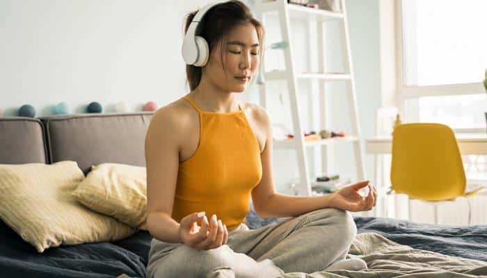 young woman meditating on bed