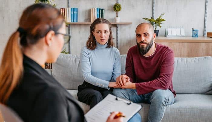 young couple holding hands talking to therapist