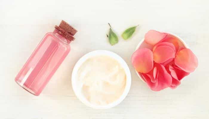 rose petals and oil bottle next to ointment