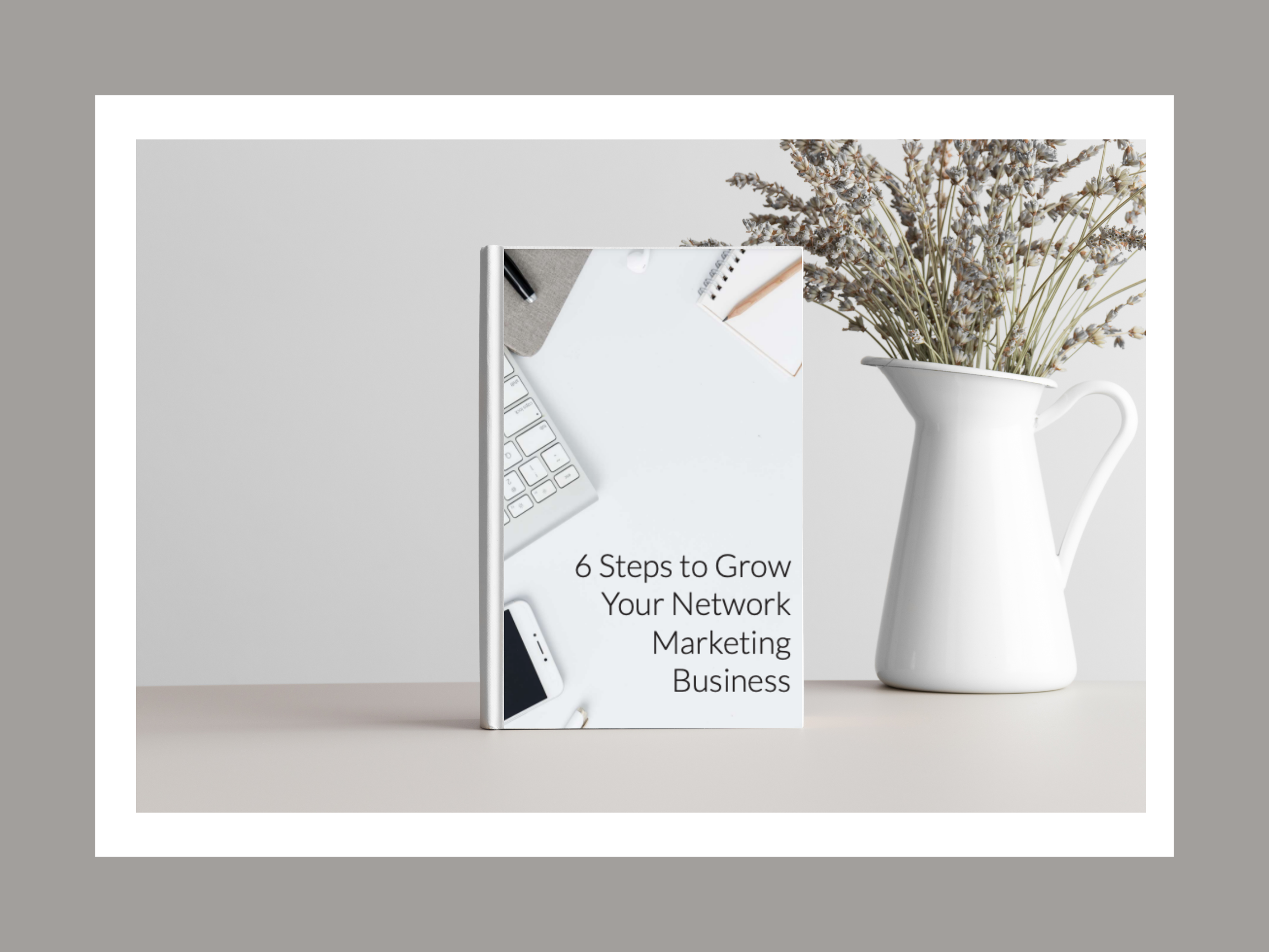 6 Steps to Grow Your Wellness Business eBook sitting up right next to flowers in a white vase