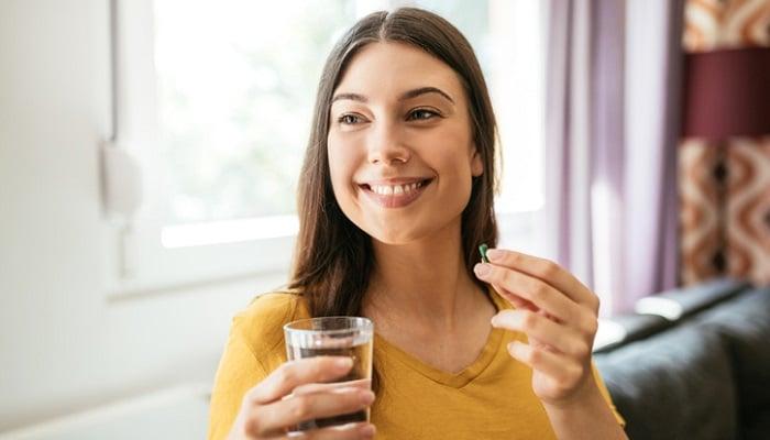 young woman taking supplement for oily skin