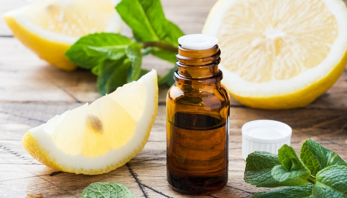 lemon next to mint leaves and essential oil bottle