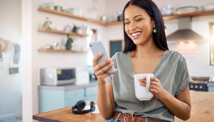 smiling young woman in kitchen looking at phone