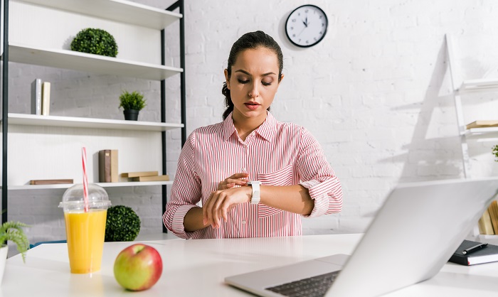 young woman at desk looking at watch