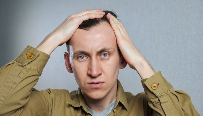 man looking at receding hairline in mirror