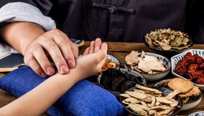 Chinese herb practitioner assessing patient's pulse