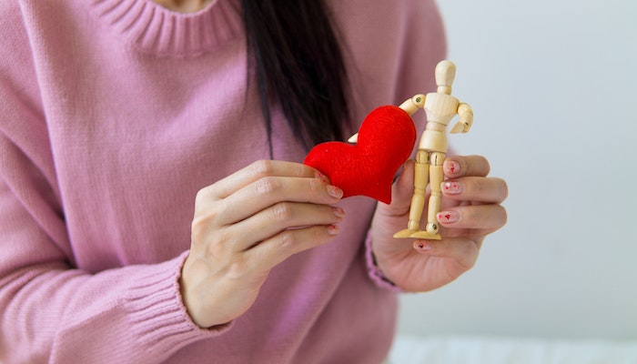 woman holding heart piece next to stick figure