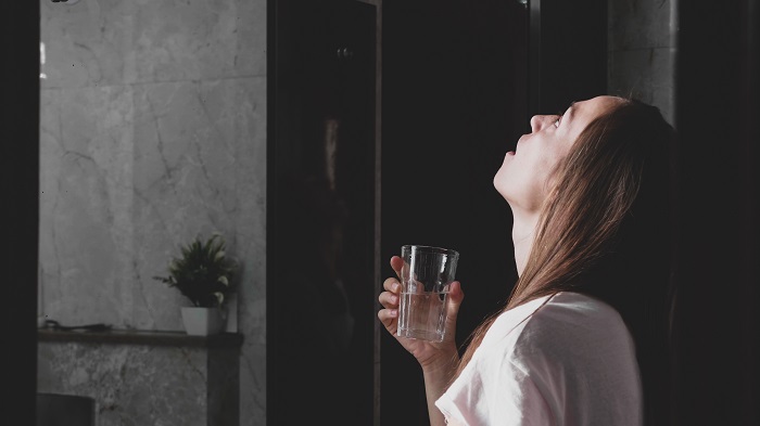 young woman gargling with essential oils for sore throat