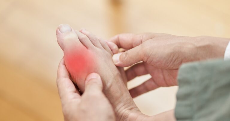 painful gout - man holding foot