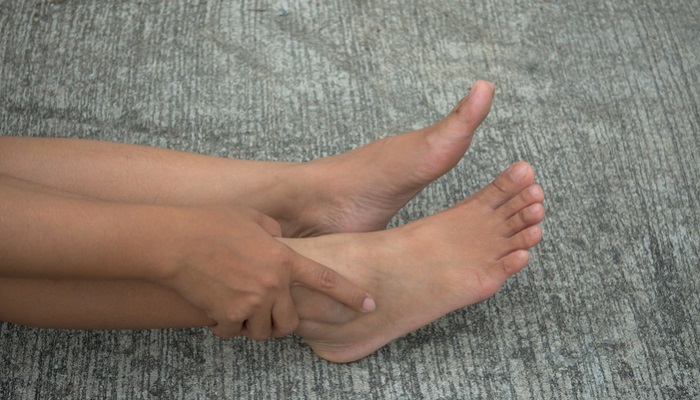 woman stimulating ankle acupoint