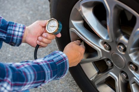 man measuring car tire pressure